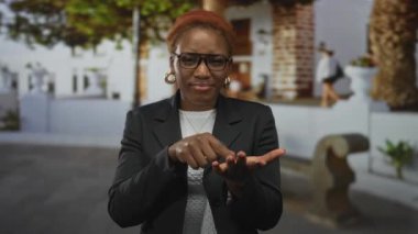 Genç Afro-Amerikalı kadın, parmağıyla sokakta açık avucunu gösteriyor; para acil savunma talep ediyor.