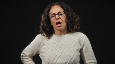 Siyah bir arka planda, karın ağrısını ifade eden bir kadın, rahatsızlık ve duygu belirtisi gösteriyor..