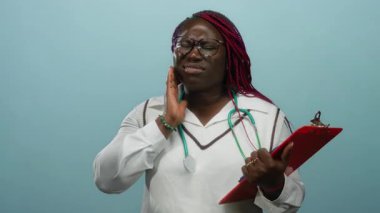 Beyaz önlüklü kadın, mavi arka planda yanak ve pano ağrısı çekiyor. Bu da diş sorununu gösteriyor..