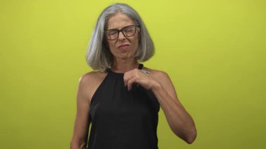 Kireç yeşili stüdyoda sırt ağrısı gösteren el ele duran kadın; orta yaş sağlık farkındalığı rahatsızlığı.