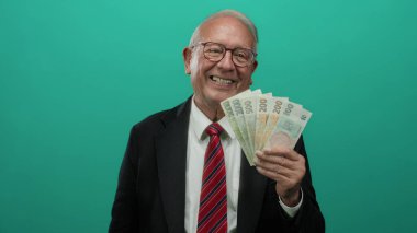 Üst düzey bir adam yeşil bir altyapının önünde Czech Koruna banknotlarını tutarak iş başarısını ve zenginliğini resmediyor..