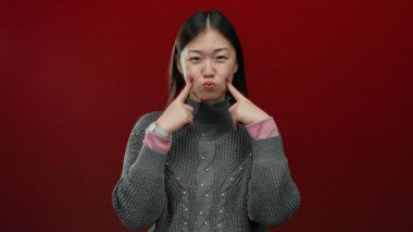 Kadın oyuncu bir ifade takınıyor kırmızı arka plan süveteri stüdyo Asyalısı