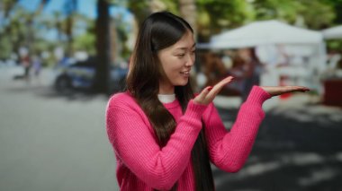 Pembe kazaklı kadın şehir caddesinde açık gökyüzü arkaplanlı canlı şehir ortamını gösteriyor..