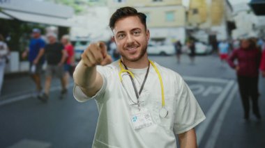 Kamerayı gösteren sakallı genç bir erkek doktor. Şehir sokaklarında steteskop takıyor. Yayalar ve şehir geçmişi bulanık..