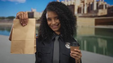 Kadın polis, tarihi bir arka planda elinde kahve ve kese kağıdıyla güvenle ayakta duruyor..