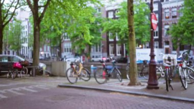 Park halindeki bisikletlerle, yemyeşil ağaçlarla ve tarihi binalarla bulanık bir kanal sahnesi, sakin bir kentsel caddenin özünü yakalıyor..