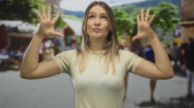 Canlı bir şehir caddesinde abartılı jestler yapan genç bir kadın, bulanık insanlarla çevrili, açık bir şehir ortamında şaşkınlık ve duygu taşıyor.