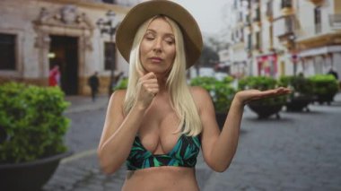 Meşgul bir kaldırım taşı sokakta kolları açık güneş şapkası takan ve göğüsleri açıkta olan bir kadın; belirsizlik..