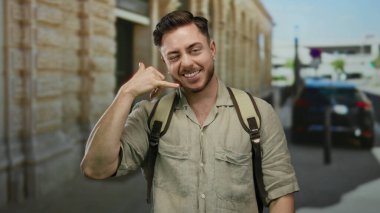 Genç sakallı turist, bir şehir caddesinde bana el kol hareketi yapıyor. Sıradan bir tişört ve sırt çantası giyiyor. Arkadaşça ve cana yakın bir tavır sergiliyor..