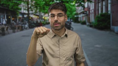 Genç İspanyol adam gözlüklü omuz silkiyor ve palmiyeler hareketli bir şehir caddesinde yukarı döndü; belirsizlik.