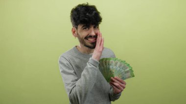 Sarı arka planda Rus rublesi tutan adam kendinden emin görünüyor ve fısıldıyor..