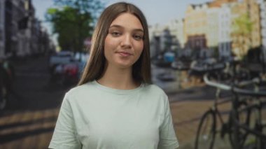 Genç beyaz kız gülümseyen avuç içini açık tutuyor ve güneşli caddede parmağıyla işaret ediyor. Meraklı keşifler merak uyandırıyor..