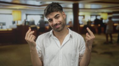 Genç İspanyol adam, yoğun bir otel resepsiyonunda para hareketinde bulunuyor..