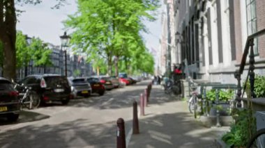 Amsterdam Caddesi 'nde park halindeki arabalar ve ağaçlarla birlikte güneşli bir günde şehrin cazibesini yakalayan Bokeh efektinin odaksız görüntüsü..
