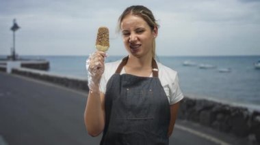 Dondurmalı dondurma tutan bir kadın açık bir eldiven içinde bir sokak gezinti, dil dışarı ve göz kırpma; neşeli yaz.