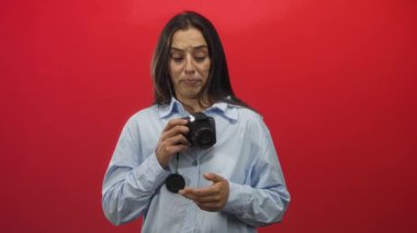 Genç İspanyol kadın göğsüne yakın bir yerde kamera tutuyor. Bir eli panjurda, diğeri de kırmızı bir stüdyoda göğsünde. Sürpriz..