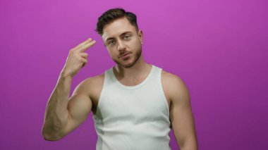 Sakallı genç bir adam, parmaklarıyla canlı pembe bir arkaplan üzerinde beyaz bir atlet, duygularını kapalı gözlerle ifade ederek dramatik bir sahne yaratıyor..