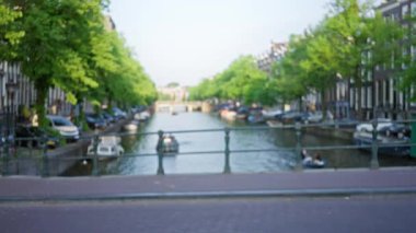 Teknelerde ve ağaçlarda insanların dolaştığı bulanık kanallar huzurlu bir şehir manzarası yaratıyor.