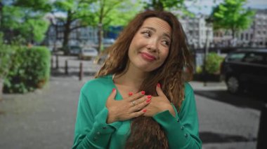 Göğüs üstü göğüsleri olan bir kadın, park halindeki arabaların ve ağaçların yakınındaki bir caddede yüzük takıyor..