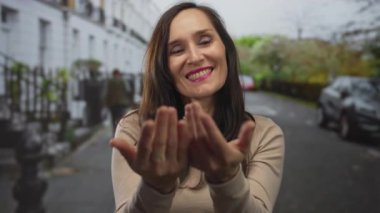 Latin kökenli genç bir kadın şehir merkezinde el pençe divan duruyor. Sevecen selamlaşma samimiyeti..