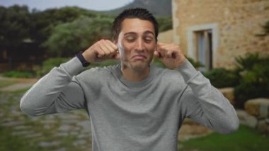 Gözlerine yumruk atan genç İspanyol bir adam taştan bir patika ve ağaçların yakınındaki bir parkta ağlıyormuş gibi yapıyor. Üzüntü..