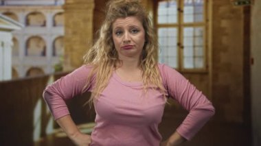 Eski şehirde kalçaları üzerinde gülümseyen bir kadın, balkon inşa ediyor pembe kazak giyiyor ve sarı saçları dökülüyor, neşeli görünüyor, kendine güveni tam..