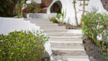 Lanzarote, İspanya 'da bulanık, açık bir patika. Yeşil ve beyaz binalar, sönük ve huzurlu bir arka plan sağlıyor.