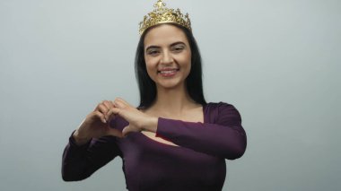 Taçlı bir kadın beyaz arka plana karşı kalp hareketi yapıyor. Mutluluk, güzellik ve kendine güven gösteriyor..