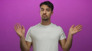 Hispanik bir adam canlı pembe bir arka plan önünde belirsizlik işareti yapıyor, beyaz bir gömlek giyiyor, kararsızlık ve kafa karışıklığını yansıtıyor..