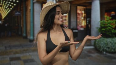 Hasır şapkalı İspanyol kadın, kaldırım taşı kaldırımlı bir sokak atari salonunda gece hayatı mağazalarının önünde ellerini açık gösteriyor..