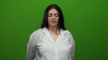 Beyaz gömlekli bir kadın canlı yeşil bir arka plana karşı duruyor, özgüven ve bireyselliği ifade ediyor, stüdyo ışıklarının altında onun artı boyutunu ve kıvrımlı figürünü vurguluyor..