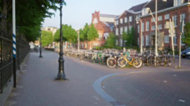 Bulanık Avrupa şehir caddesi yolu boyunca parkedilmiş bisikletlerle ve güneşli bir günde arka planda tarihi tuğla binalarla.