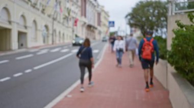 Lüks bir Monako caddesinde yürüyen bir kadın, arka planda bulanık insanlar ve arabalarla, şehir zarafeti ve açık hava eğlencesi sergiliyor..