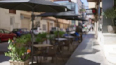 Güneşli bir günde Avrupa 'nın bir şehrinde boş masalar, sandalyeler ve şemsiyelerle bulanık bir kafeterya sahnesi