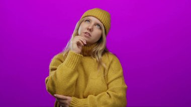 Hardal kazaklı ve bereli bir kadın parlak pembe bir arka plana karşı düşünceli bir şekilde poz veriyor. Canlı ve izole bir ortamda genç, düşünceli bir ruh haline bürünüyor..