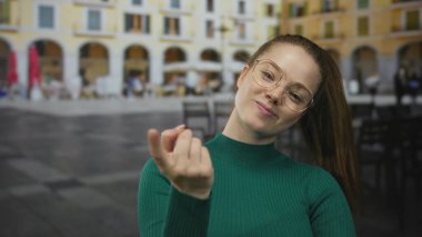 Eski şehir kafesinde gözlüklü ve yeşil kazaklı bir kadın, davetiye..