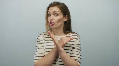 Çizgili gömlekli kadın ciddi ifade ile kollarını kavuşturuyor açık mavi stüdyoda x hareketi; reddedilme.