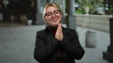 Elleri dua pozisyonunda gülümseyen bir kadın şehrin dışında neşe ve sükunet gösteriyor..