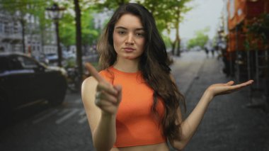 Genç İspanyol kadın yaz güneşinin altında hareketli bir şehir caddesinde sol elini kaldırıyor..