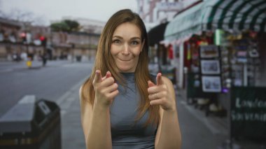Kafkasyalı genç bir kadın canlı şehir caddesinde iki parmağını doğrudan kameraya doğrultuyor..