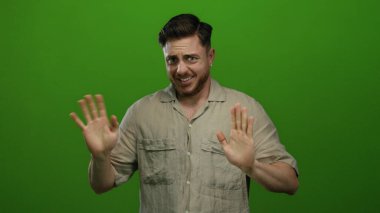 Sakallı genç adam, izole edilmiş yeşil arka plana karşı duygularını ifade ediyor..