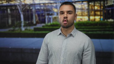 Kısa sakallı, çizgili gömlek çantalı adam. Meşgul şehir caddesinde dudaklar. Akşam ışıkları altında..