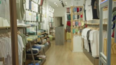 Giysiler ve parlak ışıklandırmayla bulanık bir dükkan. Dağınık rafları ve rafları olan rahat bir perakende satış ortamı yakalıyor..