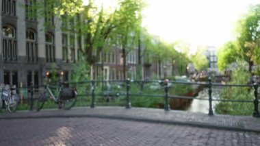 Tarihi binaların ve ağaçların bulanık, gün ışığında bisiklet süren kadın, sakin kentsel yaşam ve Avrupa mimari atmosferini yakalıyor.