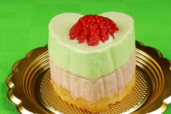 緑のテーブルクロスの上に白い磁器プレート上にハート型のイチゴとキウイババリアクリームデザート バベレー — ストック写真