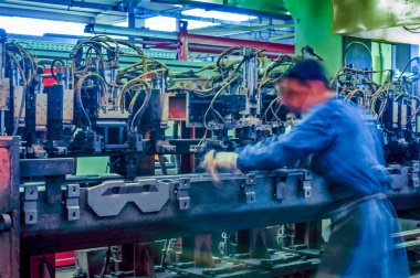 Koruma maskesi olan işçiler büyük bir makine aracı üzerinde çalışıyorlar