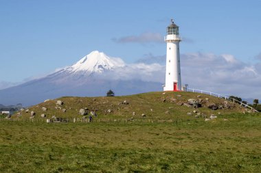 Arka planda Taranaki volkanı olan Cape Egmont deniz feneri, Yeni Zelanda
