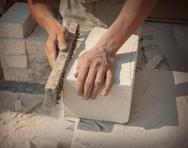 The sculptor's hands, which process a block of white stone on the desktop with tools. Hand Detail