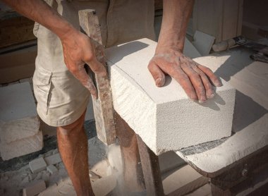 The sculptor's hands, which process a block of white stone on the desktop with tools. Hand Detail
