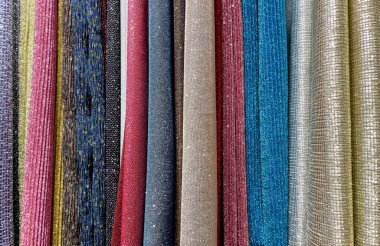 Mağazada çok renkli perdeler var. Çok renkli kumaşların dokusu, yakın çekim. Çok renkli kumaş örnekleri. Yakın plan. Bir mağazada asılı çok renkli kumaş. Kumaş rengi ve doku örnekleri.